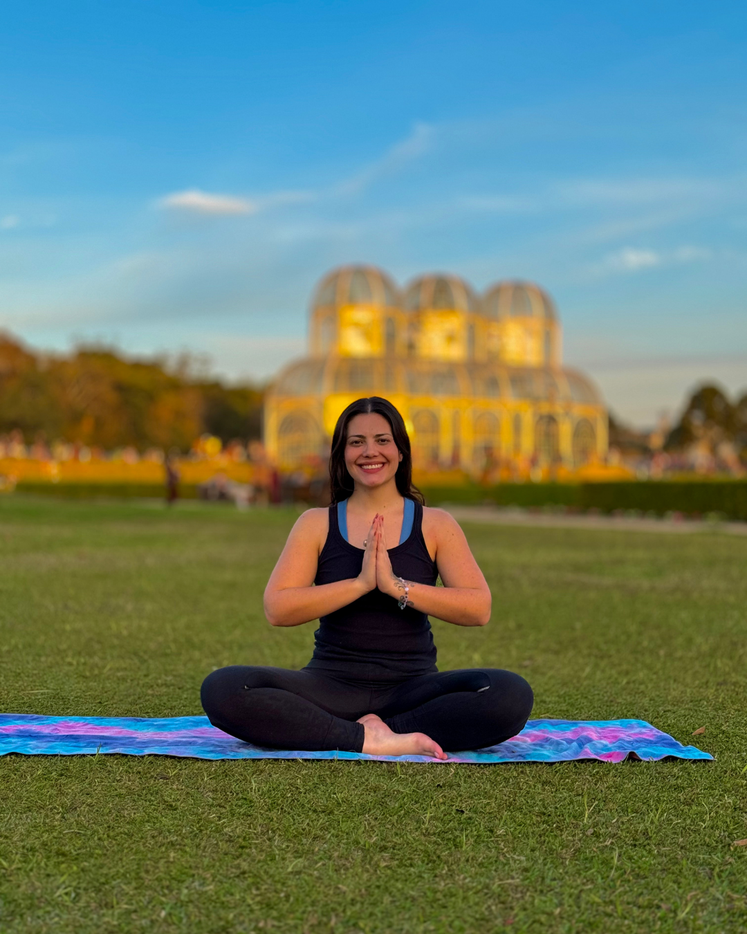 Jess Cristini, professora particular de Hatha yoga online, sorrindo em um estúdio iluminado